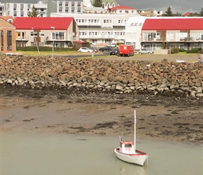 A red boat picks out the red rooved houses in Borganes