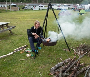 Siobhan cooks sausages over an open file at Holman Camping